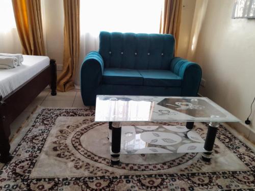 sala de estar con sofá azul y mesa de centro de cristal en Galene Abode Studio Apartment, Nyali, en Mombasa