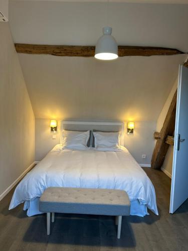 a bedroom with a white bed with a bench on it at Jolie grange rénovée. in Couches