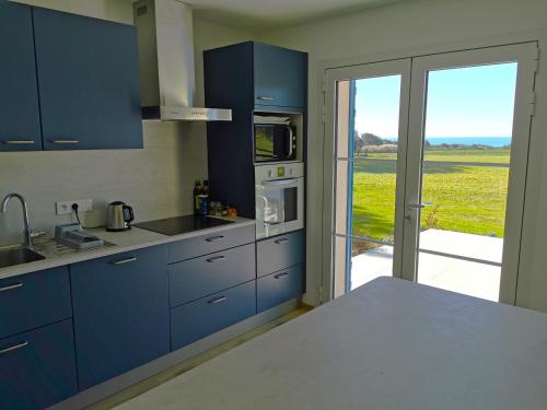 une cuisine avec des armoires bleues et une vue sur un champ dans l'établissement Port Jure Face a la mer, à Les Sables-dʼOlonne