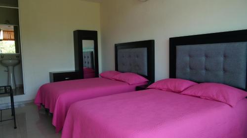 two beds in a room with pink sheets at Hotel Mar Caribe Puerto Vallarta in Puerto Vallarta