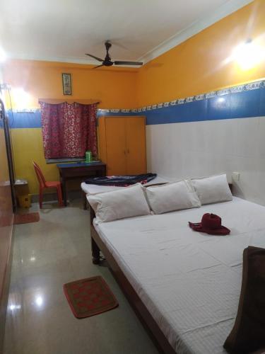 a bedroom with three beds and a table with a red hat at PAYEL LODGE in Digha