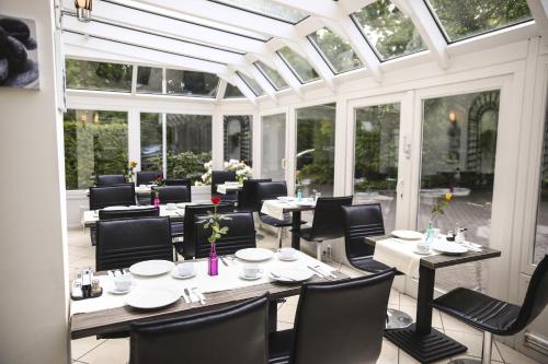 a dining room with tables and chairs in a conservatory at Hotel Marienthal Garni in Hamburg