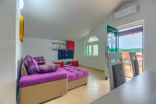 a living room with a purple couch and a kitchen at Apartmani Mato in Pirovac