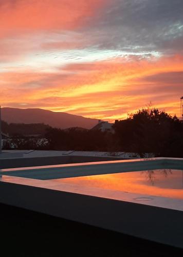 a sunset over a swimming pool at sunset at One of a Kind #PDL Luxury Retreat in Ponta Delgada