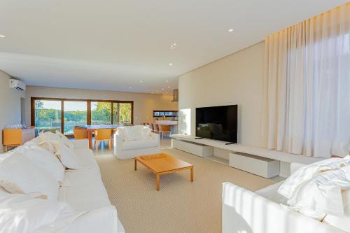 uma sala de estar com mobiliário branco e uma televisão em SA09 Excelente Casa 5 Suítes - Reserva Sauipe em Mata de São João