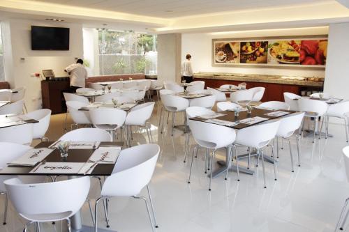 a dining room with white tables and white chairs at Mesón de la Luna Hotel & Spa in Mérida