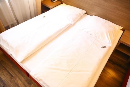 a bed with white sheets on a wooden floor at Hotel Marienthal Garni in Hamburg