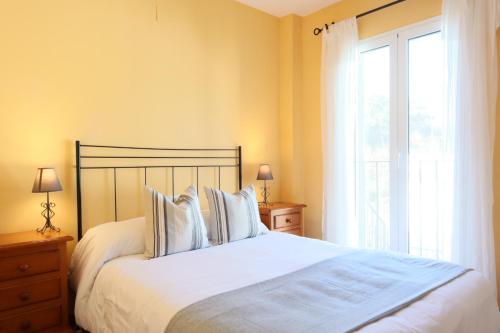 a bedroom with a bed with white sheets and a window at Casa La Buganvilla 2 Aracena in Aracena