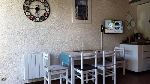 une salle à manger avec une table, des chaises et une horloge dans l'établissement Au coeur du Golf de Lacanau Océan, à Lacanau