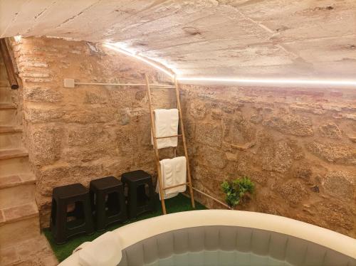 bañera en una habitación con pared de piedra en 'El Charcón' Casa con piscina compartida, en Torrico