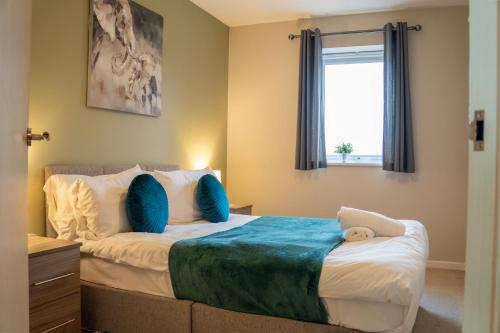 a bedroom with a large bed with blue pillows at Modern Two Bedroom Apartment with Free Parking, Wifi & Sky TV by HP Accommodation in Milton Keynes