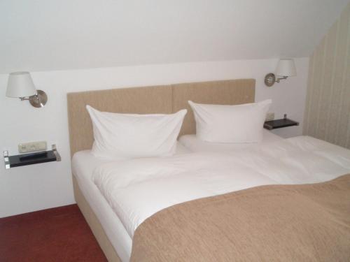 a bed with white sheets and pillows in a room at Hotel Doberaner Hof in Bad Doberan