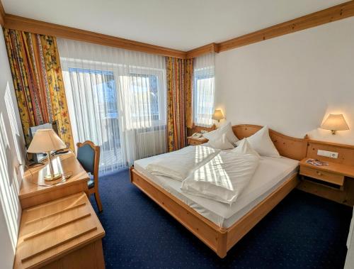 um quarto de hotel com uma cama, uma secretária e janelas em Hotel Heinz em Brunico