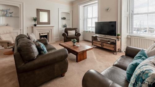 uma sala de estar com dois sofás e uma televisão em At Anchor (with a Harbour View) em Fife