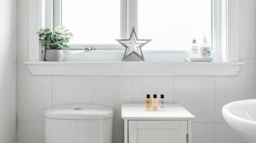 a white bathroom with a toilet and a window at At Anchor (with a Harbour View) in Fife