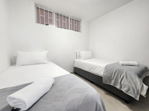 two beds in a room with white walls at Penzance by the beach in Durban