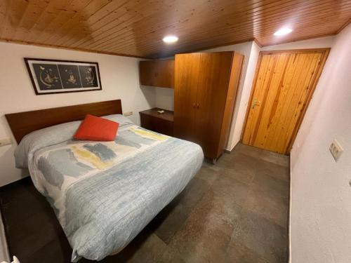 Dormitorio pequeño con cama con almohada roja en casa rústica, en Olot