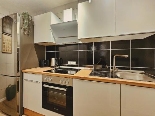 una cocina con armarios blancos y fregadero en Modern & Comfortable Apartment Stuttgart - Netflix - 4K TV - waipu en Korntal-Münchingen