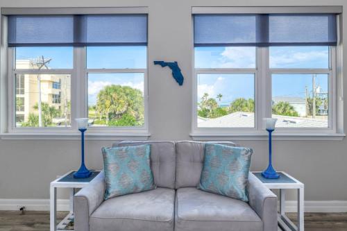 a living room with a couch and three windows at Oceans 13 Condo D in Saint Augustine Beach