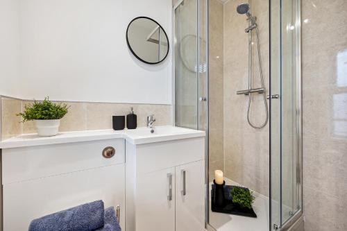 ein Bad mit einer Dusche, einem Waschbecken und einem Spiegel in der Unterkunft Stockport Retreat - Double En-suite - Great transport links - Greater Manchester in Stockport