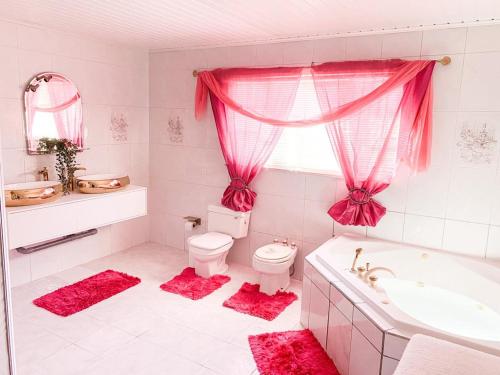 La salle de bains rose est pourvue de toilettes, d'une baignoire et d'un lavabo. dans l'établissement Tropical Retreat Stay Aruba, à Oranjestad