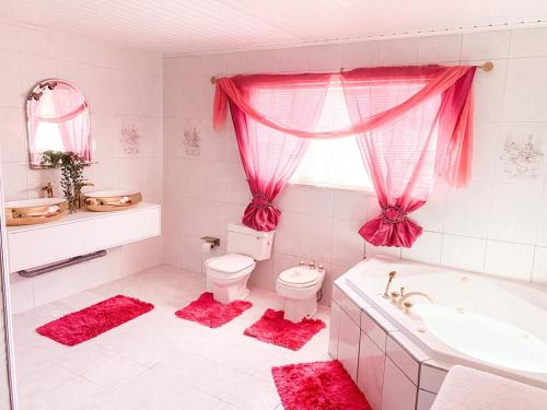 a pink bathroom with a toilet and a tub and a sink at Tropical Retreat Stay Aruba in Oranjestad