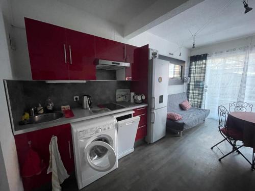 - une cuisine avec des placards rouges et un lave-linge dans l'établissement Le Mouflon Résidence Olympe, T2 centre ville 4 personnes, Parking privatif gratuit, Prise Green Up véhicule électrique, Possibilité forfait ménage et location linge de lit et de toilette, à Font-Romeu-Odeillo-Via