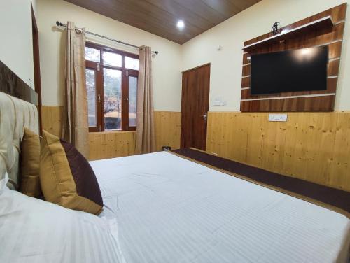 a bedroom with a bed with a flat screen tv at Vintage Woods Inn in Shimla