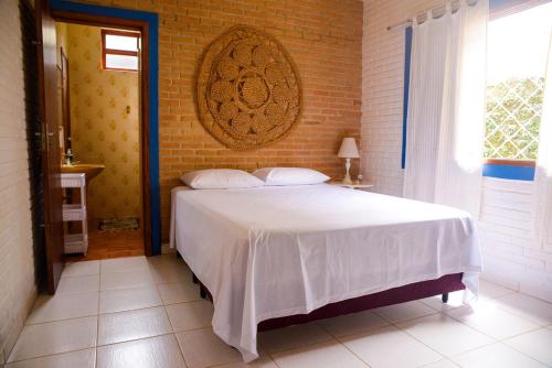 - une chambre avec un lit blanc et un mur en briques dans l'établissement Otima casa c Wi Fi 8 min da praia Barequecaba SP, à São Sebastião