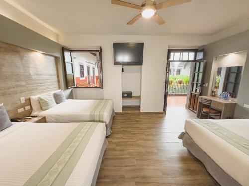 a hotel room with two beds and a flat screen tv at Hotel Hidalgo in Querétaro