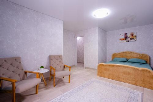 a bedroom with a bed and two chairs and a table at 1 комнатная квартира в центре города на Гоголя 42А in Kostanay