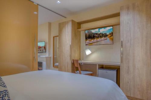 una camera con letto bianco e scrivania di Suite Quadruplo 7 dias - Wyndham Gramado Termas Resort & Spa a Gramado