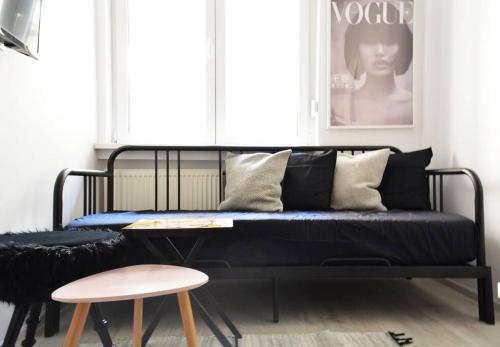 a black couch in a room with a table and stool at 2 Bdr / Cozy Ap Near Old Town in Bucharest