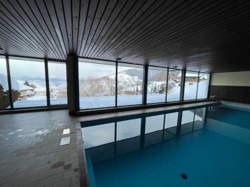 una piscina con vistas a una montaña nevada en 2,5 pièces à Haute-Nendaz, grande terrasse, piscine, sauna, tennis, en Nendaz