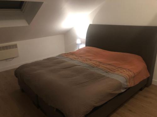 ein Bett in einem Schlafzimmer mit einem Licht an der Wand in der Unterkunft Logement entier sur Wormhout in Wormhout