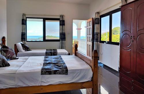 two beds in a room with a view of the ocean at Villea Frangipani in Mahe