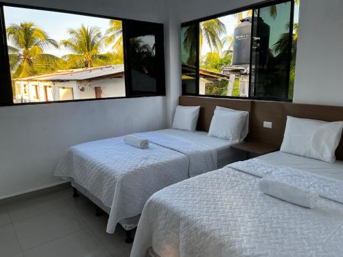 two beds in a room with two windows at Hotel Paseo del Sol in La Paz