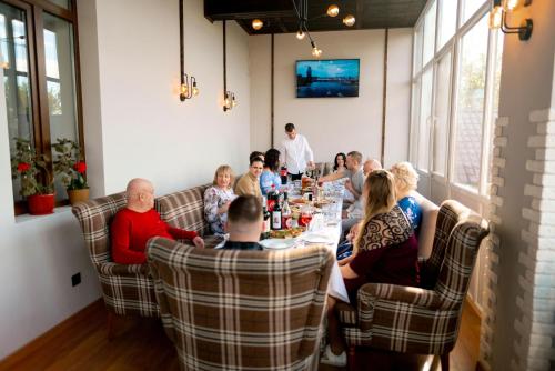 a group of people sitting around a table in a restaurant at Райский Дворик in Pogreby