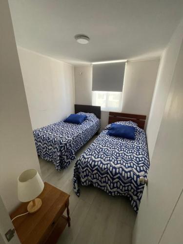 a room with two beds and a table with a lamp at Hermoso Depto Piscina in Rancagua