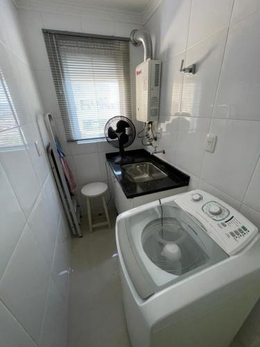 eine kleine Küche mit Spüle und Waschmaschine in der Unterkunft Apartamento com 3 suítes a 300 metros da praia em edifício com piscina in Itapema