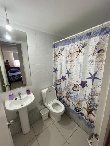 a bathroom with a toilet and a sink and a shower curtain at Hermoso Depto Piscina in Rancagua