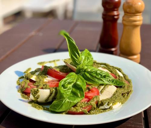 a white plate of food with greens on a table at Райский Дворик in Pogreby