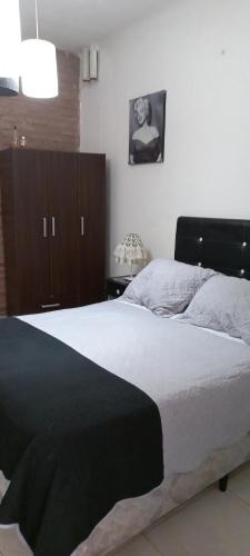 1 dormitorio con 1 cama con edredón blanco y negro en Anita en Villa Mercedes