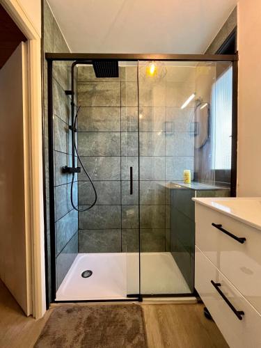 y baño con ducha y puerta de cristal. en Appartement neuf à 400 m des remontées avec Sauna, en La Chapelle-dʼAbondance