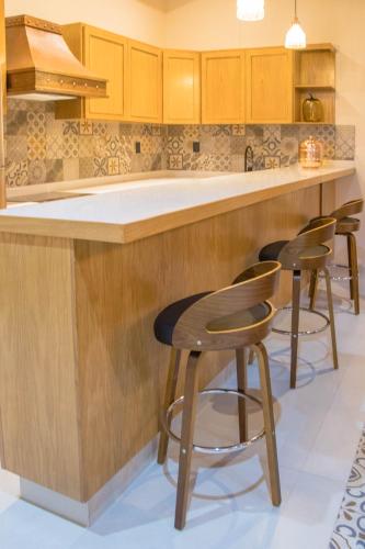 a kitchen with wooden cabinets and bar stools at Casa Cairo Pátzcuaro in Pátzcuaro