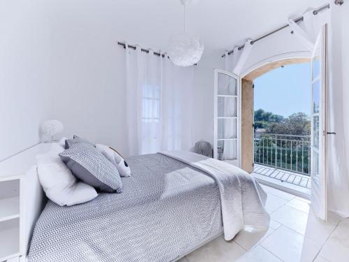 a white bedroom with a bed and a balcony at Bastide d'Architecte en Pierre in Cagnes-sur-Mer