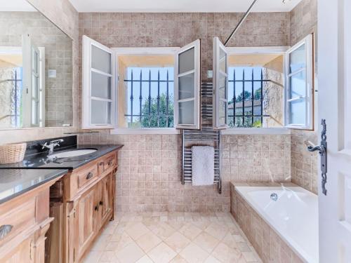 uma casa de banho com uma banheira, um lavatório e janelas em Bastide d'Architecte en Pierre em Cagnes-sur-Mer