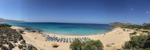 a beach with people and umbrellas and the ocean at Falassarna Beach studios&apartments in Falasarna