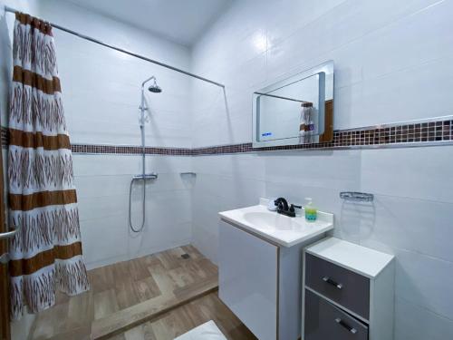 a white bathroom with a sink and a shower at RÉSIDENCES MOROLA - SENA in Dakar