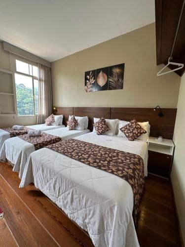 a row of four beds in a hotel room at Pousada Princesa Isabel - Visconde in Petrópolis